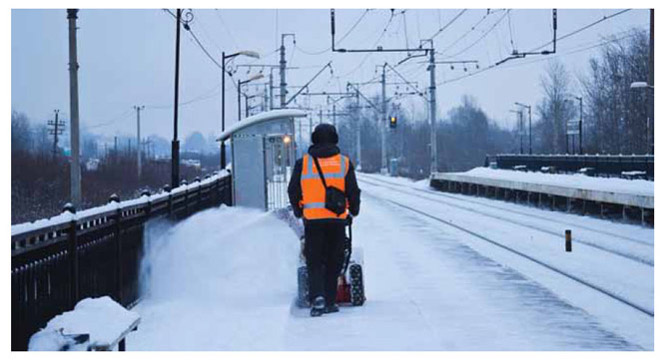 Image of worker manually operating snowblower